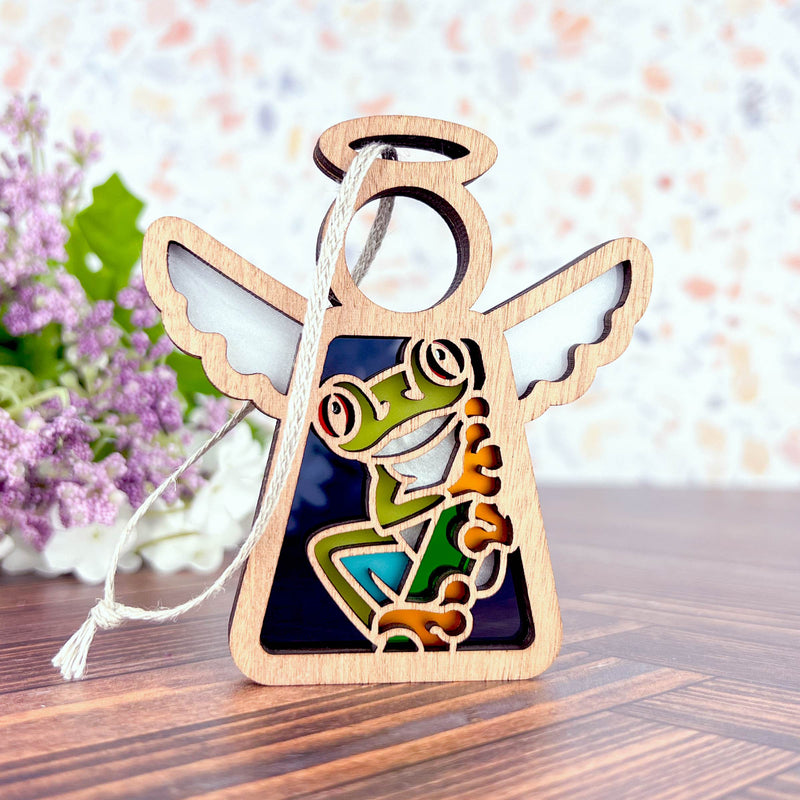 The Forged Flare® Red-Eyed Tree Frog Ornament is a 3.5" Mother's Angels® figurine with a stained-glass style frog panel—ideal as a unique gift or Christmas tree ornament. Displayed on wood, it’s perfect for frog lovers and collectors alike.