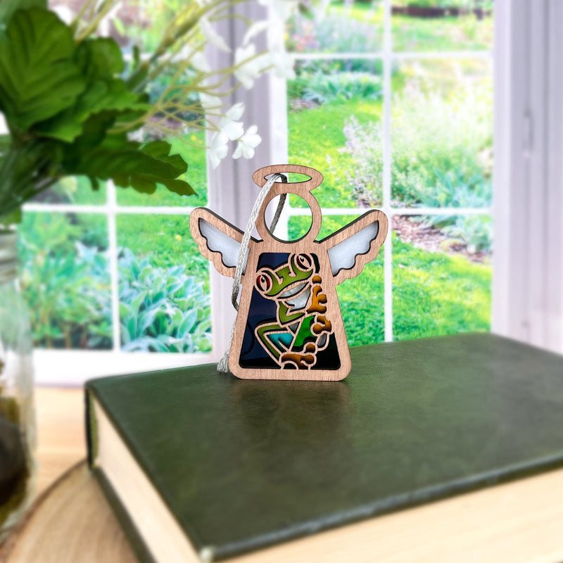 The Forged Flare® Mother's Angels® Red-Eyed Tree Frog Ornament is a charming 3.5" wooden angel figurine, featuring a frog design, perfect as a unique gift for nature lovers.