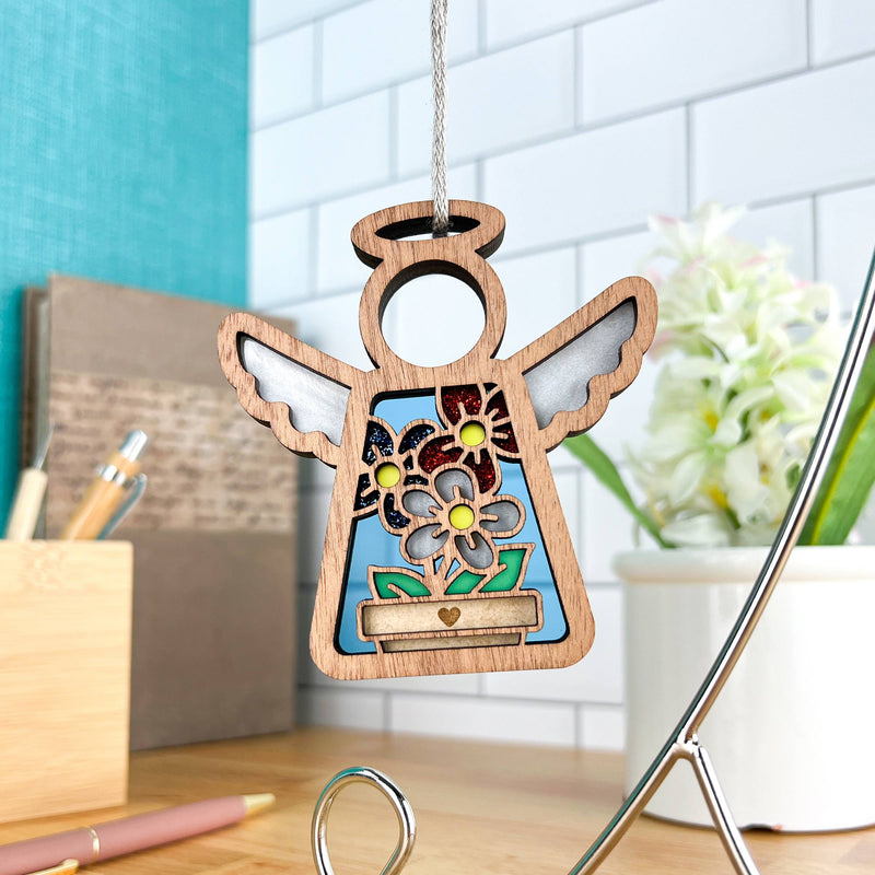 The Forged Flare® Red, White & Bloom Ornament is a 3.5" Mother's Angels® figurine featuring cut-out wings and flower accents, hanging by a string—perfect as a patriotic gift or Christmas tree ornament.