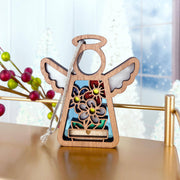 The Forged Flare® Red, White & Bloom Ornament is a 3.5" Mother's Angels® figurine featuring floral designs and gold accents, hanging by a silver string on a gold rail amid red berries and snowy trees—perfect for your Christmas tree.