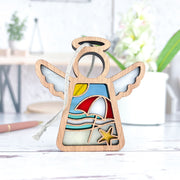 The Forged Flare® Mother's Angels® 3.5" Summer Beach Ornament features a wooden angel figurine with a red and white umbrella, sun, waves, and starfish—ideal for Christmas trees or beach house decor.