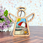The Forged Flare® Summer Beach Ornament is a 3.5" Mother's Angels® angel figurine with stained glass effect, featuring a beach scene—umbrella, waves, sun, and starfish. Ideal for beach house decor or as a unique summer accent.