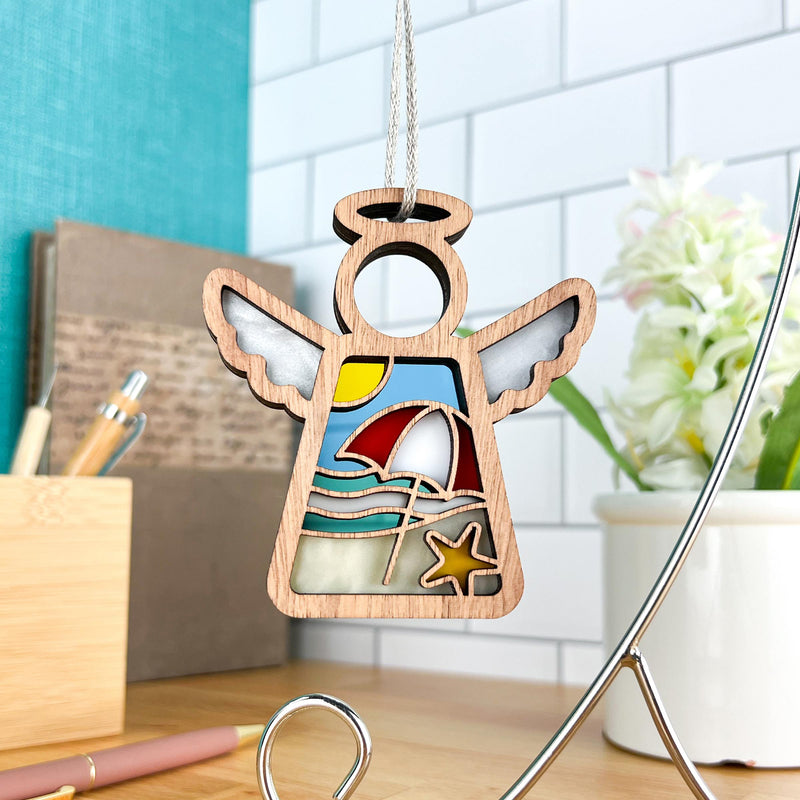 The Forged Flare® Mother's Angels® Summer Beach Ornament is a 3.5" wooden angel figurine with beach cutouts—umbrella, sun, waves, starfish—hung on a string. Ideal for beach house decor or as a unique Christmas tree ornament.