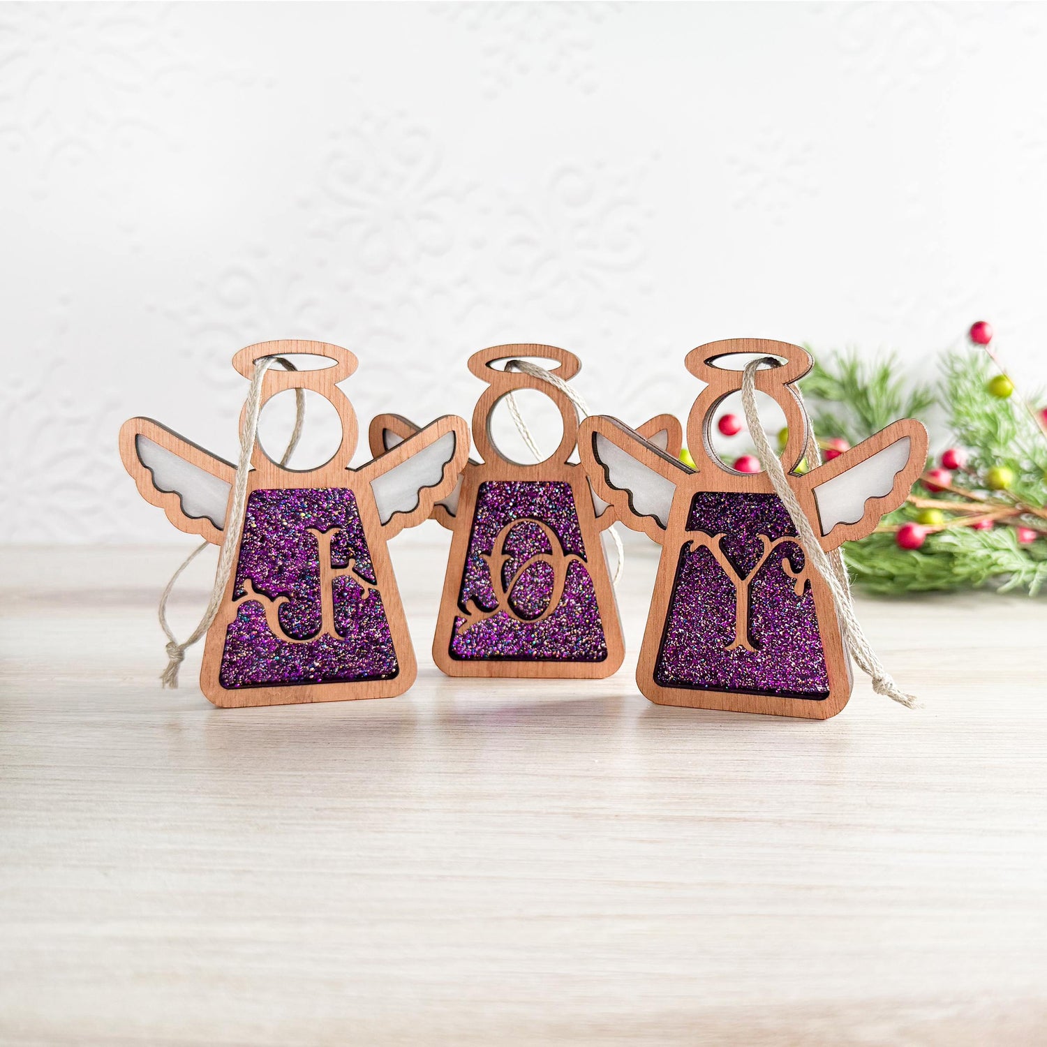 Handcrafted purple letter ornament set spelling 'JOY' with glittery initial designs, crafted as personalized Christmas ornaments for a festive holiday display.