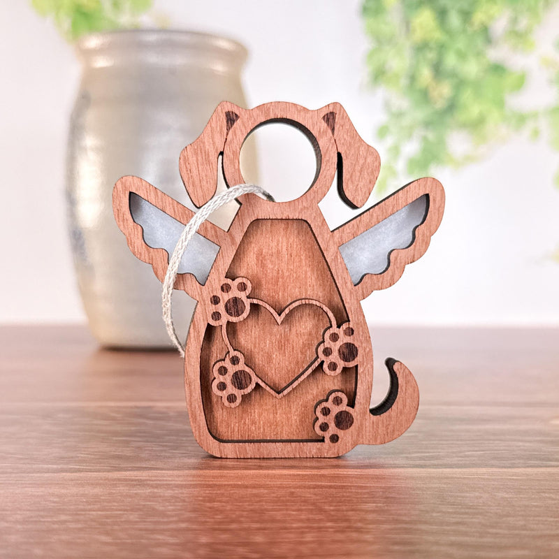 The Forged Flare® Forever In My Heart Dog Angel Ornament features wood, angel wings, a heart, and paw prints. Ideal for dog lovers, it hangs by a string and beautifully honors your pet’s memory.