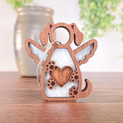 The Forged Flare® Forever In My Heart Dog Angel Ornament is a heartfelt wooden keepsake with wings and a heart, perfect as a dog lover gift or memorial. It includes a hanging loop, shown resting on wood with soft greenery in the background.