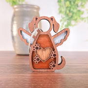 The Forged Flare® Forever In My Heart Dog Angel Ornament, featuring a heart and angel wings with cut-out details and a hanging string, sits on wood—perfect as a dog lover gift.