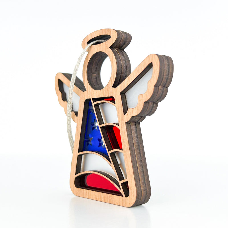The Forged Flare® American Flag Ornament is a 3.5" Mother's Angels® figurine with halo, white wings, and a red and blue dress. It hangs by twine—perfect as a patriotic gift for the holidays.