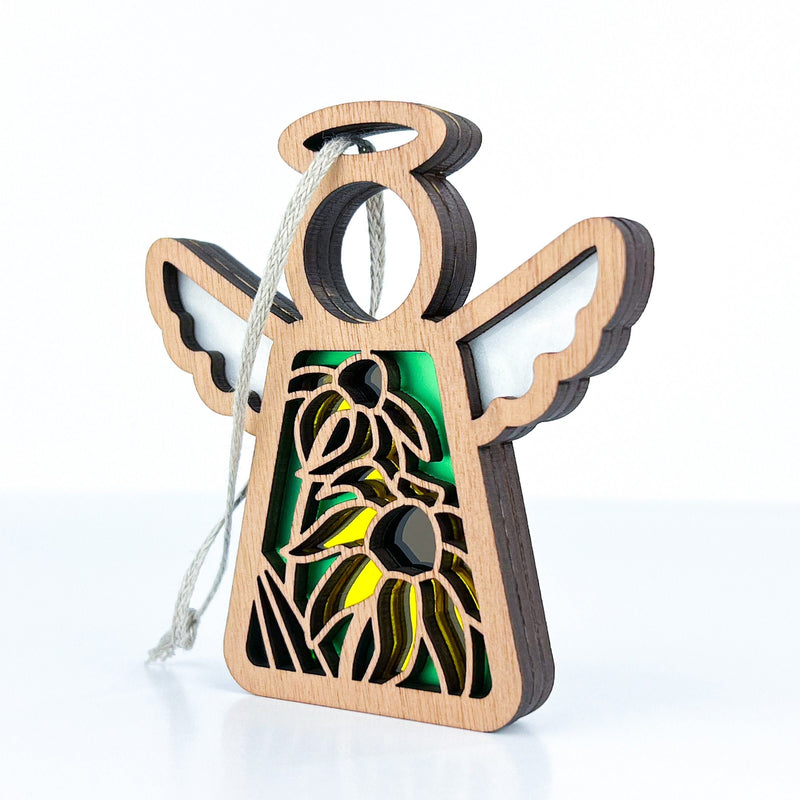 The Forged Flare® Black-Eyed Susan Ornament is a 3.5" Mother's Angels® wooden angel figurine with wing and halo, cutout yellow Black-eyed Susans on green, and a gray hanging string—perfect as a Christmas ornament.