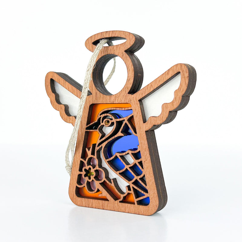 The Forged Flare® Mother's Angels® Blue Jay Ornament is a 3.5" wooden angel figurine with white wings, blue jay and pink flower details, and a string halo for hanging—an ideal bird lover or memorial gift for any occasion.