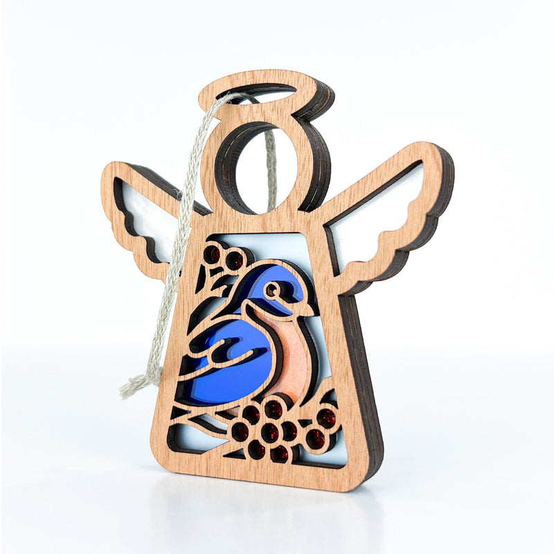 The Bluebird Ornament by Forged Flare® is a 3.5" wooden Mother's Angels® figurine featuring a blue bird with red accents and outstretched wings, finished with a twine loop—perfect as a memorial or bird lover gift.