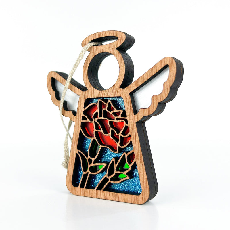 The Forged Flare® Carnation Ornament is a 3.5" Mother's Angels® angel figurine featuring cut-out wings, a stained glass-style carnation and green leaf design on blue, with a hanging string attached to one wing.
