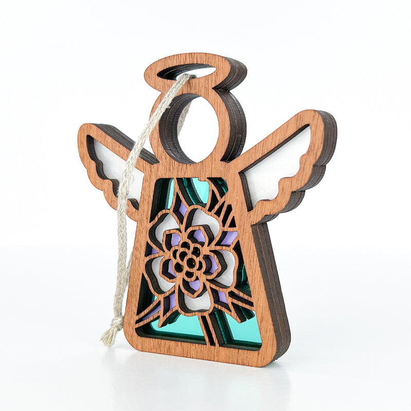 The Forged Flare® Columbine Ornament is a 3.5" wooden Mother's Angels® angel figurine with a cut-out columbine flower, purple and teal hues, white-accented wings, dark edges, and a hanging string for display.