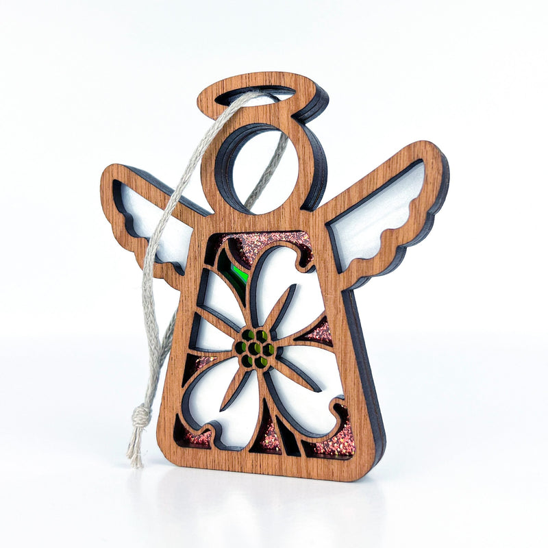 Introducing the Dogwood Ornament from Forged Flare®, a 3.5" angel figurine from the Mother's Angels® collection. This wooden ornament features white wings, a halo, and a large flower cutout in the center. It is adorned with glittery accents and has a looped string at the top for easy hanging, set against a plain white background. Perfect for adding charm to your Christmas tree!