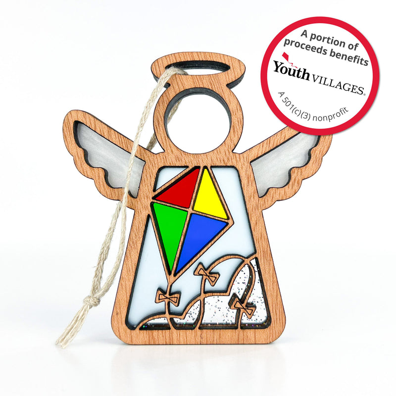 The Forged Flare® Fly A Kite for Charity Ornament is a 3.5" Mother's Angels® wooden angel with a colorful kite, hanging string, and circular tag noting that proceeds support Youth Villages, a 501(c)(3) nonprofit. Great for Christmas or beach house decor.