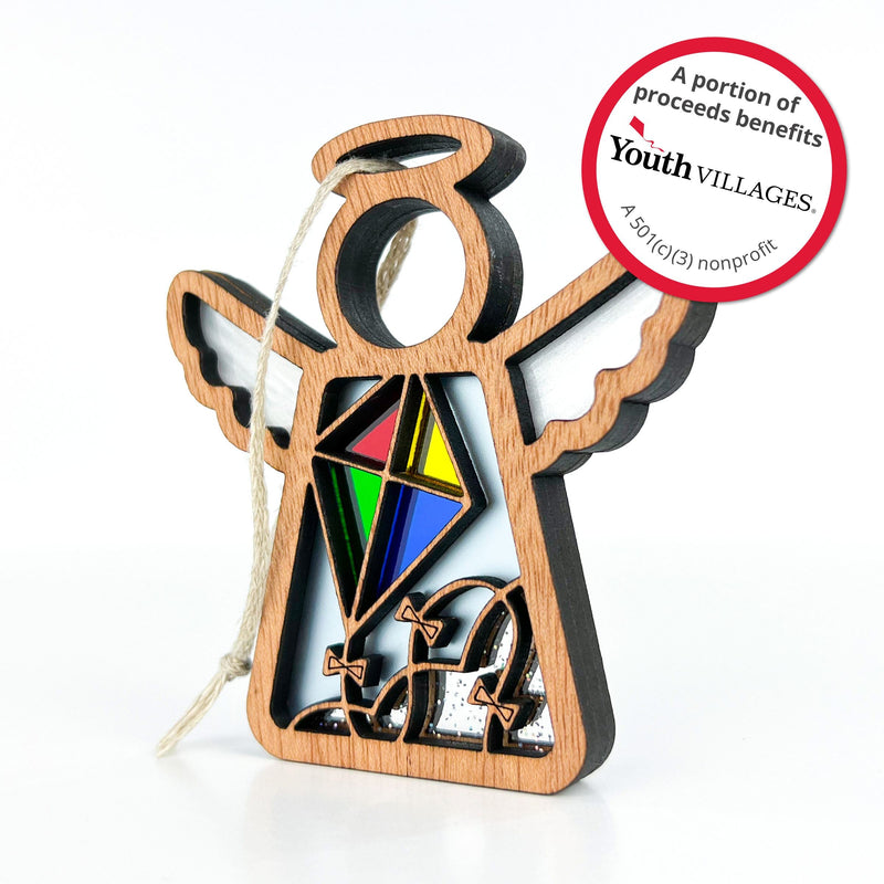 The Forged Flare® Fly A Kite for Charity 3.5" Mother's Angels® ornament features a wooden angel with kite and wave designs, a hanging string, and supports Youth Villages, a 501(c)(3) nonprofit, with every purchase. Ideal beach house decor.