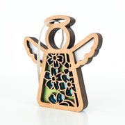 The Forget-Me-Not Ornament by Forged Flare® is a 3.5" wooden angel figurine with floral cutouts, blue and green accents, white wings, and a hanging loop—ideal for gifting or as décor. Features the Mother's Angels® design on a white background.