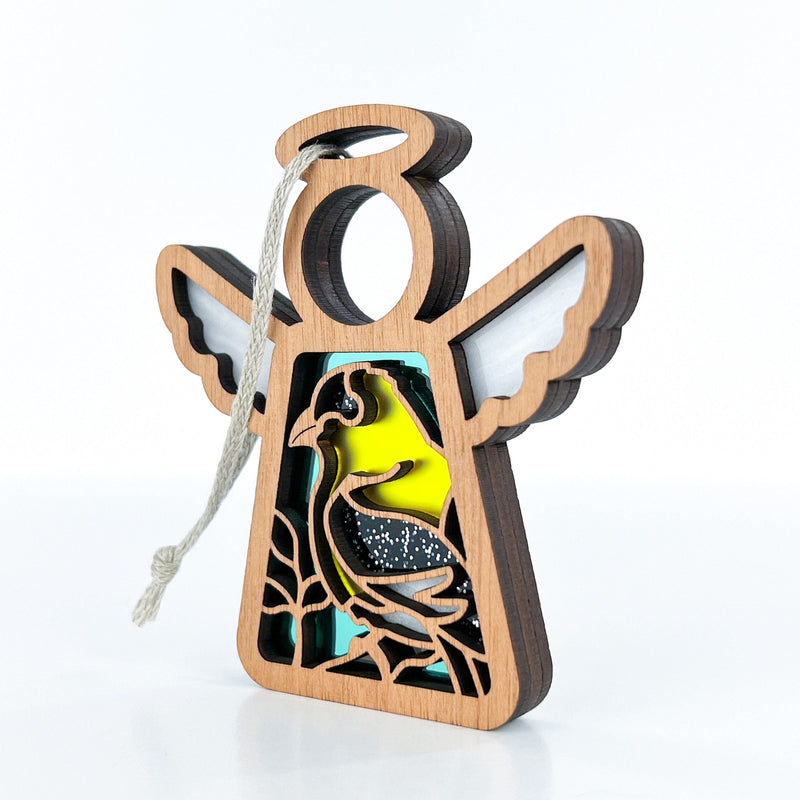 The Forged Flare® Goldfinch Ornament is a 3.5" tall wooden Mother's Angels® angel figurine with a hollow center, decorative bird and plant accents, colored details, and a hanging string—an ideal gift for bird lovers or bird watchers.