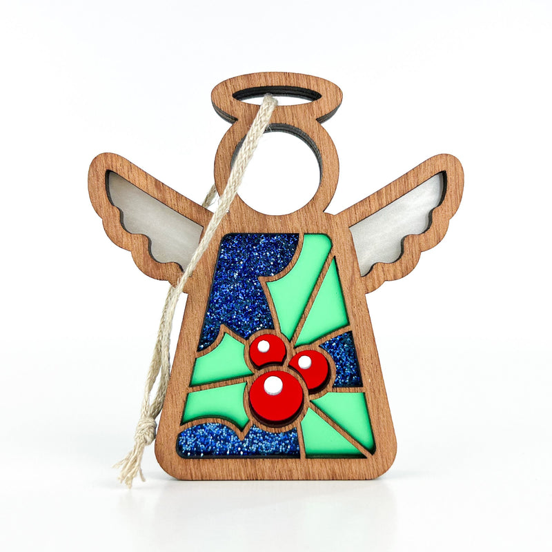 The Forged Flare® Holly Ornament is a 3.5" Mother's Angels® figurine with cutout wings, halo, twine loop, blue glitter body, and green holly with red berries—perfect for December's birth flower theme.