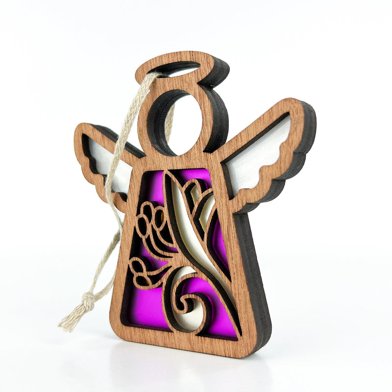 The Forged Flare® Honeysuckle Ornament is a 3.5" Mother's Angels® wooden angel figurine with white wings, halo, honeysuckle flower cutout, and hanging string, shown against a white background with a soft purple backdrop.