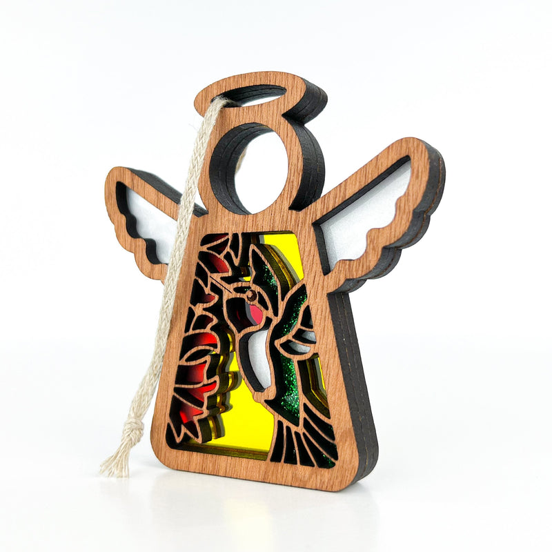 A 3.5" wooden angel figurine from Forged Flare® Mother's Angels®, featuring a stained-glass style ruby-throated hummingbird design, white wings, halo, and hanging loop. This is a warehouse return ornament.