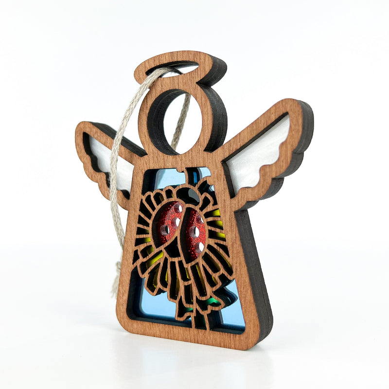 The Forged Flare® Ladybug and Dandelion Ornament is a 3.5" Mother's Angels® figurine with white wings, a halo, and a red ladybug on a yellow flower, complete with string for hanging as a unique Christmas tree ornament.