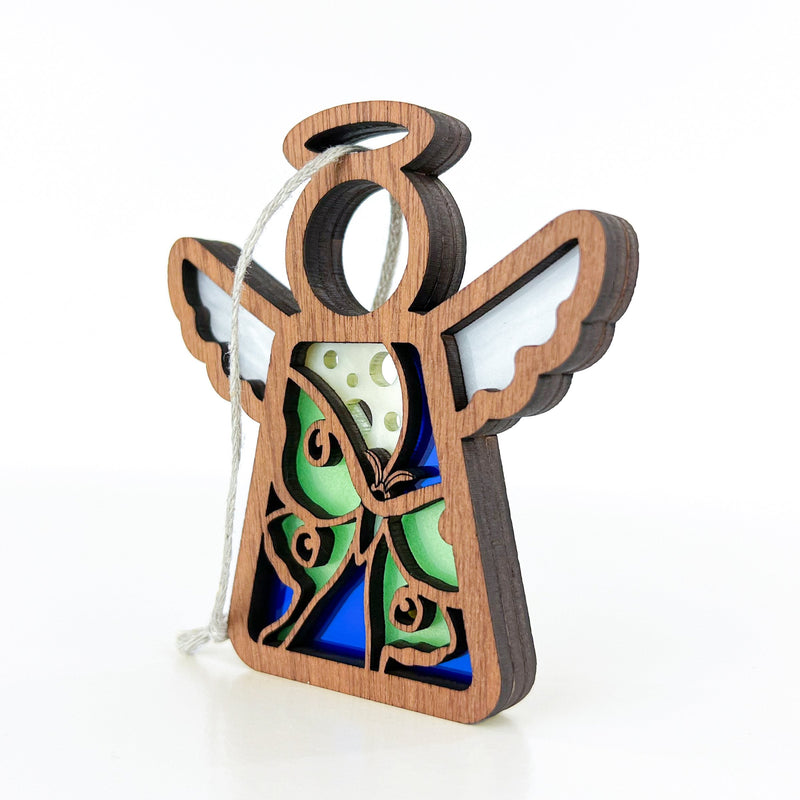The Forged Flare® Luna Moth Ornament is a 3.5" wooden angel figurine from Mother's Angels®, featuring green and yellow butterfly wings, blue stained glass, and a white hanging string for a whimsical touch to your tree.