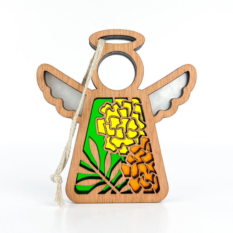 The Forged Flare® Marigold Ornament is a 3.5" wooden angel figurine from Mother's Angels®, featuring a cut-out floral design with bright marigolds on green and a white hanging string.