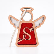 The Forged Flare® Personalized S Monogram Ornament is a 3.5" wooden angel figurine from Mother's Angels®, featuring white wings, a red glittery center with a cursive "S," and a white hanging string against a plain background.