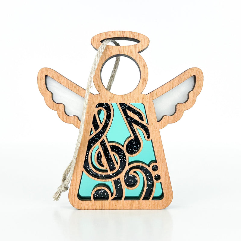 The Forged Flare® Mother's Angels® Music Ornament is a 3.5" wooden angel figurine with teal and black music notes, white wings, and a halo—ideal for music lovers or as a thoughtful gift for a music teacher.