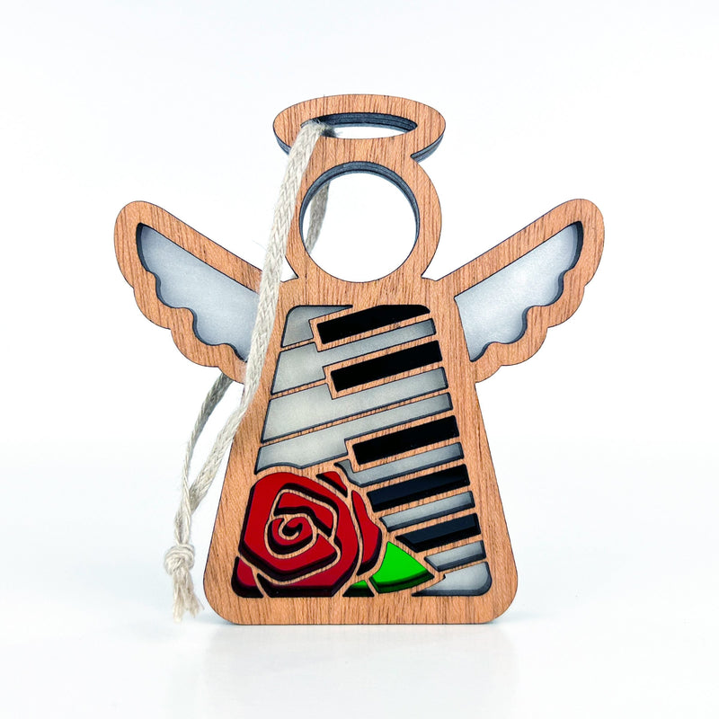 The Piano & Rose Ornament with Imperfections by Forged Flare® is a 3.5" handcrafted wooden Mother's Angels® figurine, featuring stained glass-inspired wings, piano keys, a red rose at the base, and a hanging string—perfect for collectors.