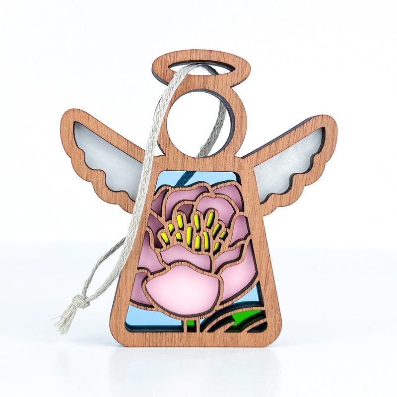 The Forged Flare® Mother's Angels® Pink Peony Ornament is a 3.5" tall wooden angel with frosted white wings, a large pink peony with yellow stamens and green leaves, and a string for hanging—perfect for your Christmas tree.