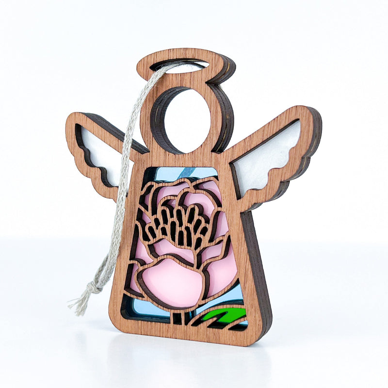 The Forged Flare® Pink Peony Ornament is a 3.5" Mother's Angels® wooden angel with cut-out wings, a string loop, and a stained glass-style floral design featuring pink flowers and green leaves.