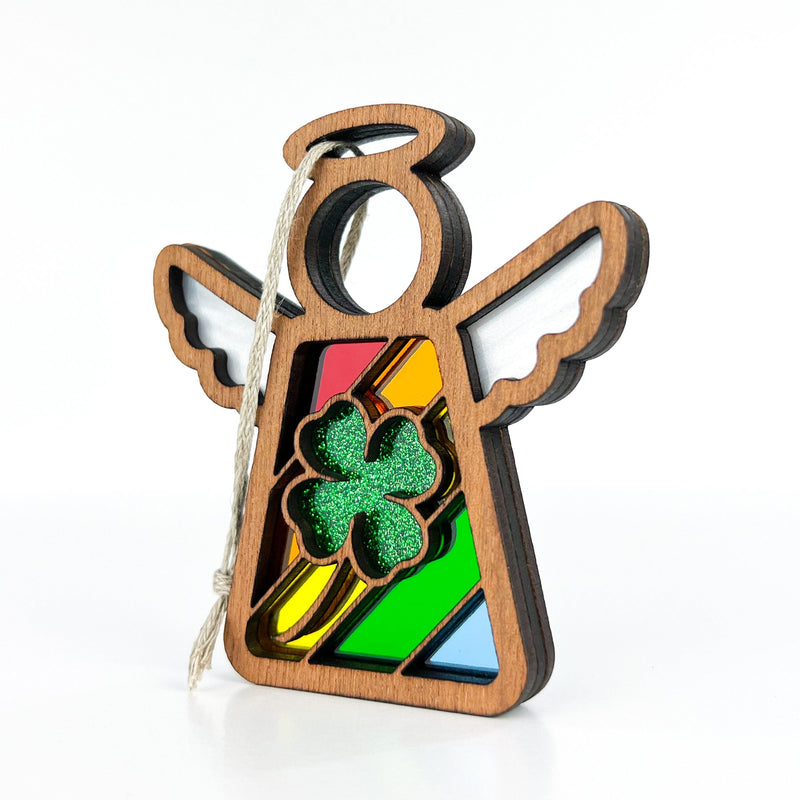 The Forged Flare® Glittery Four-Leaf Clover Ornament features a 3.5" Mother's Angels® figurine with white wings, a red, yellow, green, and blue stained-glass style body, a sparkling green clover center, and an attached hanging string.