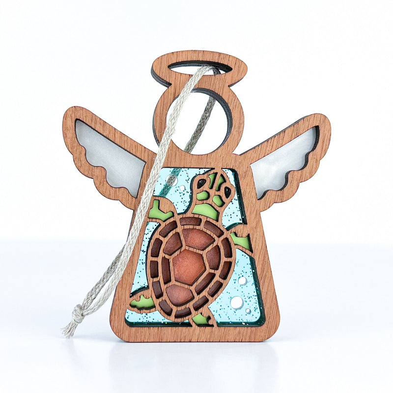 The Forged Flare® Sea Turtle Ornament is a 3.5" Mother's Angels® figurine with transparent wings, a brown and green turtle center, blue bubbly background, and string loop—perfect coastal decor for your beach house.