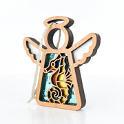 The Forged Flare® Seahorse Ornament is a 3.5" wooden angel figurine from Mother's Angels®, with outstretched wings, seahorse and ocean cut-outs, layered colorful details, and a white hanging string—perfect for Christmas trees or beach house décor.