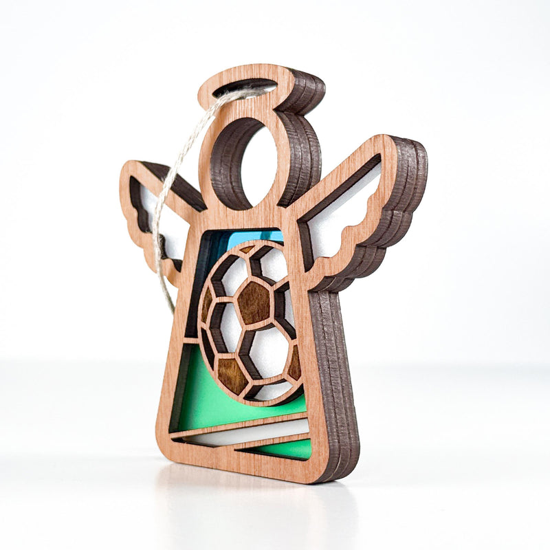 The Forged Flare® Mother's Angels® Soccer Ornament is a 3.5" wooden angel figurine with cutout wings, a soccer ball centerpiece, and green accents—perfect as a soccer goalie ornament.