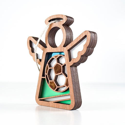 The Forged Flare® Mother's Angels® Soccer Ornament is a 3.5" wooden angel figurine with cutout wings, a soccer ball centerpiece, and green accents—perfect as a soccer goalie ornament.
