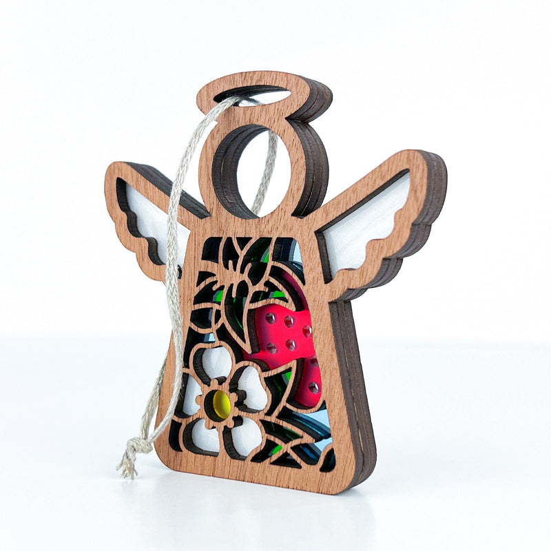 The Forged Flare® Strawberry Ornament is a 3.5" (H) Mother's Angels® wooden angel figurine with white wings, floral cutouts, red interior, and a string for hanging—ideal as a charming Christmas tree ornament on any surface.
