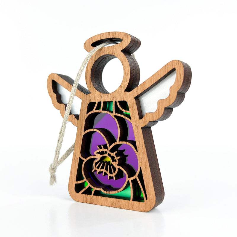 The Forged Flare® Violet Ornament with Imperfections is a 3.5" Mother's Angels® figurine, featuring white wings, a halo, and purple-yellow floral stained glass—a charming addition to any collection.