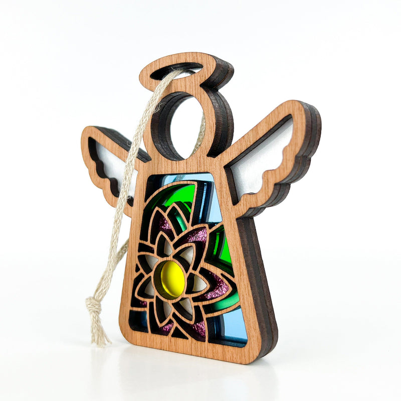 The Forged Flare® Water Lily Ornament is a 3.5" wooden Mother's Angels® angel figurine with layered wings, halo, string for hanging, and stained glass-like details featuring a water lily birth flower motif with yellow center.