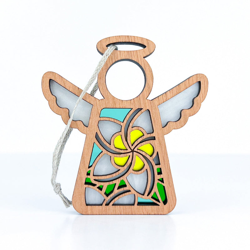 The Forged Flare® White Plumeria Ornament is a 3.5" wooden Mother's Angels® figurine with a rope for hanging, featuring a blue, yellow, and green cutout design and plumeria-inspired flower pattern on its body.