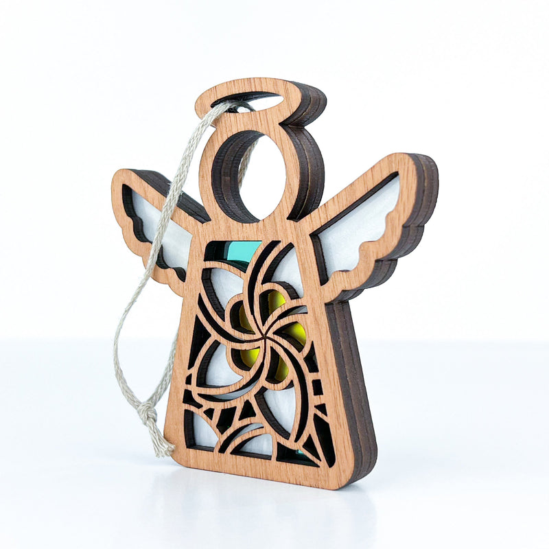 The Forged Flare® White Plumeria Ornament is a 3.5" Mother's Angels® wooden angel figurine with laser-cut patterns, colored accents, and a hanging loop, shown on a white background.