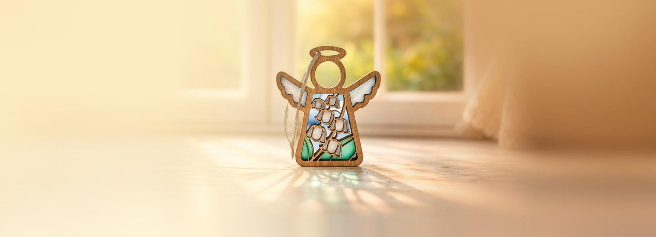 Decorative angel figurine with stained glass style design on a light surface, soft focus background