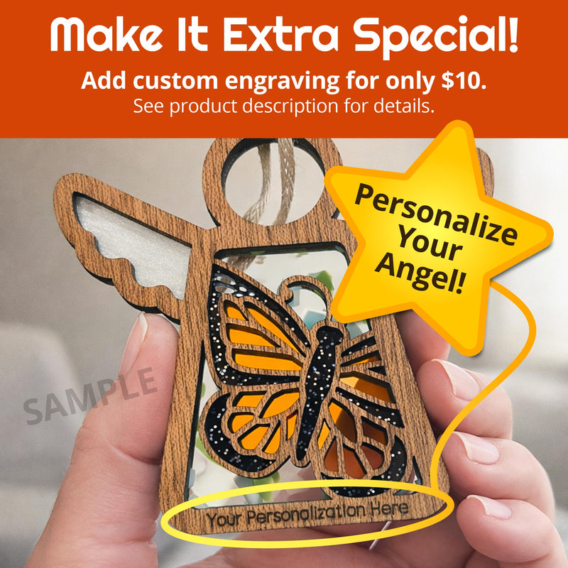 A hand holds a Forged Flare® Monarch Butterfly Ornament—a 3.5" Mother's Angels® wooden angel with a stained glass butterfly. Custom engraving available for $10; "Personalize Your Angel!" starburst and space for your text. A unique butterfly gift!.