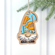 The Forged Flare® California Poppy Ornament from the Nature’s Gnomes™ collection features a blue-hatted gnome with orange poppies, white beard, and hangs by a string on a pine branch. Measures 3.75" (H).