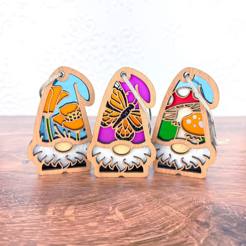 Forged Flare® Nature's Gnomes™ 3-piece bundle features 3.75" wooden gnomes with California poppy, monarch butterfly, and toadstool mushroom hats—ideal as garden decor or a whimsical gnome Christmas tree ornament gift.