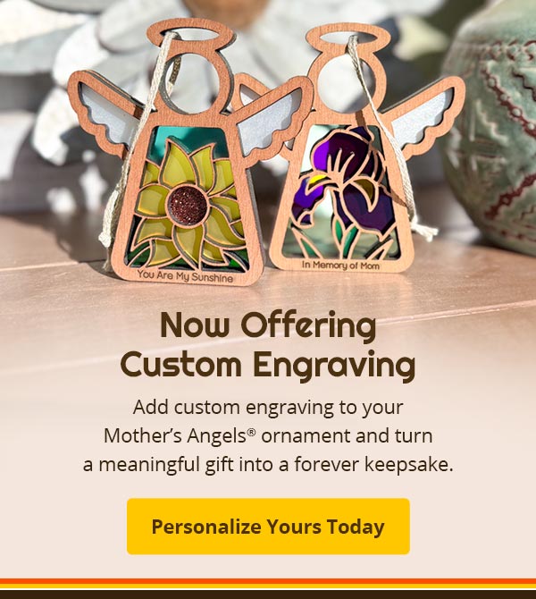 Two angel ornaments with floral designs on a wooden surface, with text about custom engraving. Text reads: Now Offering Custom Engraving. Add a custom engraving to your Mother’s Angels® ornament and turn a meaningful gift into a forever keepsake. Personalize Yours Today.