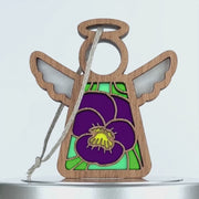 A wooden angel ornament with a halo and wings. The body of the angel features a stained glass–style design showcasing a violet flower and green leaves. A string is attached to the halo for hanging, making it a charming violet ornament for any space.