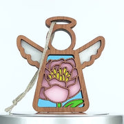 A small wooden stained glass–style angel ornament with an intricate pink peony design in the center. The angel has raised wings, a halo, and a string loop for hanging. 